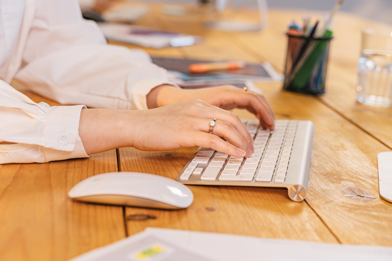 Close-up of woman's hands typing on a keyboard, showcasing modern office environment.
